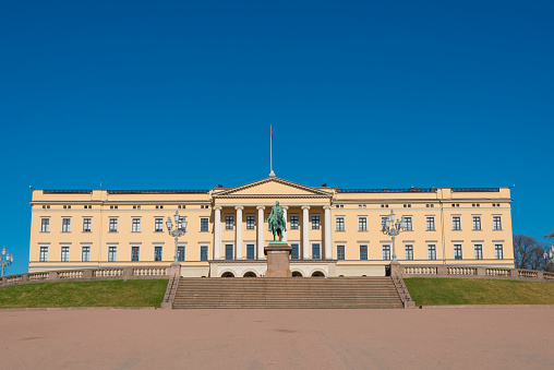 Oslo, Norway - April 26. 2018. The royal residence or royal palace is a landmark in Oslo. The wide path to the castle, which is visible from afar, is usually used by many people. However, in the early morning hardly anyone is out and about in the bright sunshine.