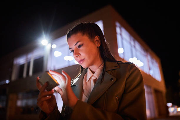istock Fashionable woman text messaging while enjoying a night walk 1257021393