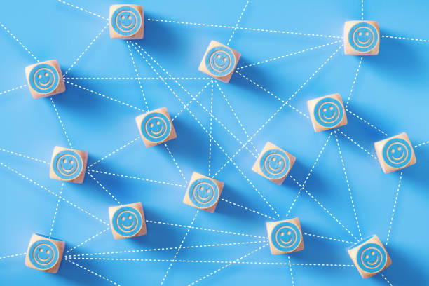 Smiley face symbols drawn blue wood blocks which are connected by dotted lines sitting on blue background. Horizontal composition with copy space. Social media and networking concept.
