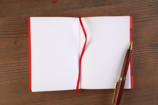 top view of open white notebook with blank page and ribbon bookmark on wood background for copy space