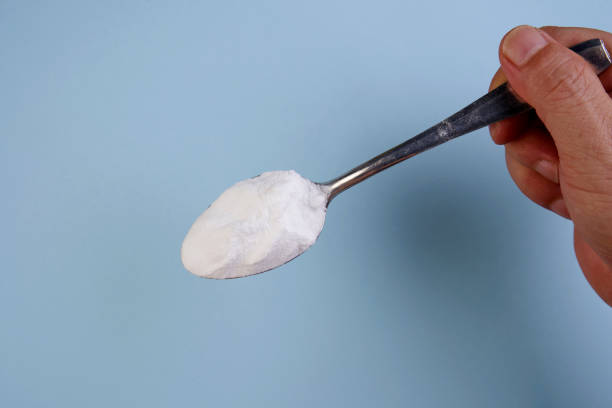 hand holding spoon of baking soda directly above of man holding spoon of baking soda on the blue background carbonate mineral stock pictures, royalty-free photos & images