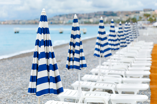 Empty beach chairs and umbrellas in a row on a beach of Nice