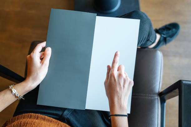woman is holding and pointing on an empty page as template texture, card, menu or brochure
