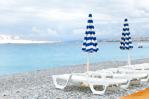 Empty beach chairs and umbrellas in a row on a beach of Nice