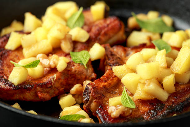 Roasted Pork chops with caramelized apples, walnuts and sage in a cast iron pan.