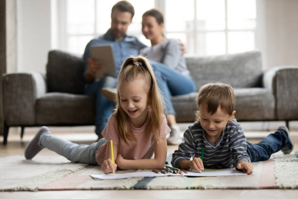 istock Little sister and brother playing on floor while parents relaxing 1257033394