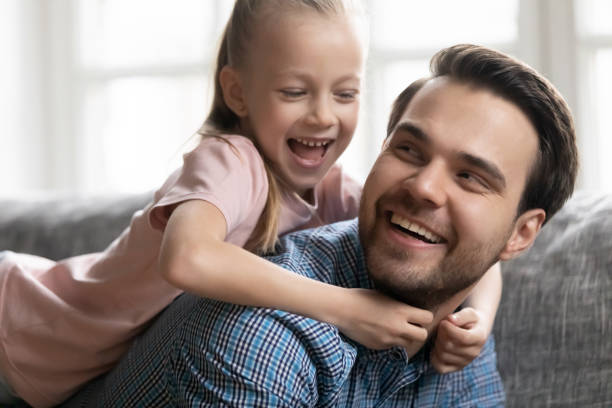istock Cute girl lying on happy father back on couch 1257033409