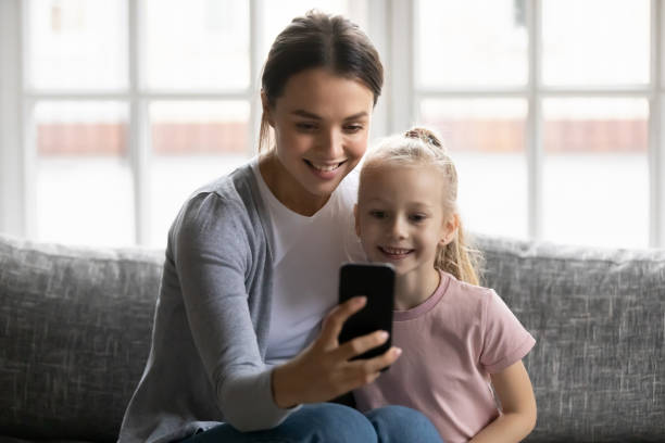 istock Smiling young mother and little daughter using smartphone together 1257033443