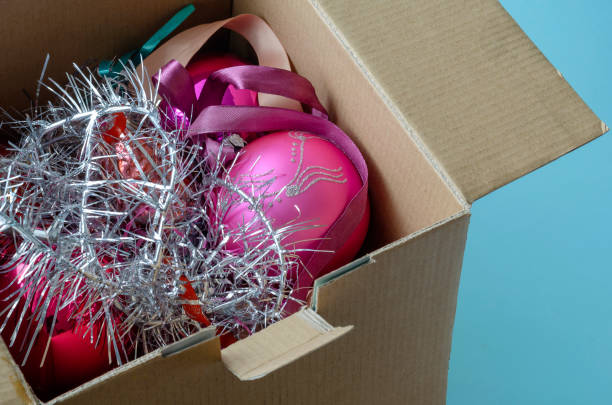 Cardboard box full of Christmas tree decorations. Cardboard box full of Christmas tree decorations. Random glass Christmas tree decorations and tinsel. Celebrating Christmas and New Year. Top view at an angle. christmas decoration storage stock pictures, royalty-free photos & images