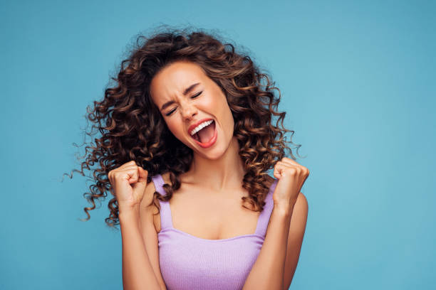 girl on a blue background rejoices at her success - surprise imagens e fotografias de stock