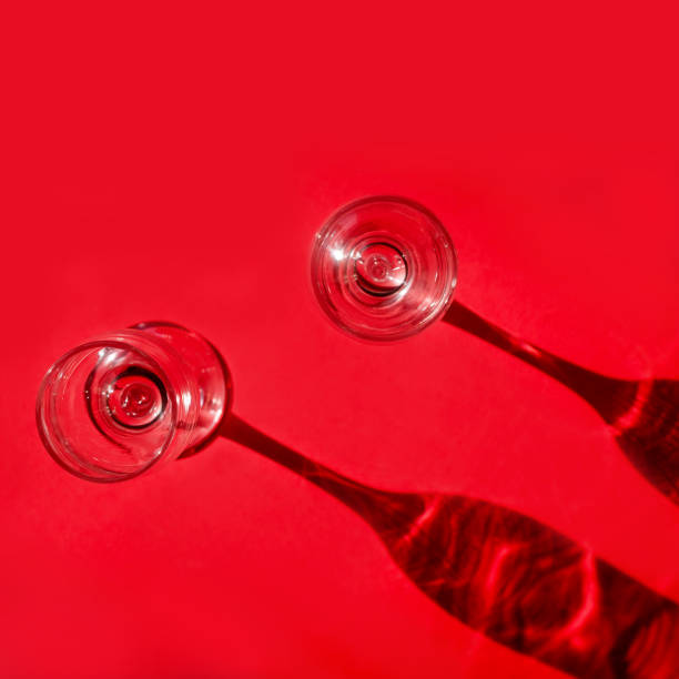 istock Two empty glasses with shadows on red background in natural sunlight . 1257039803