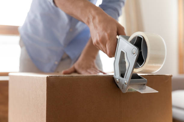 istock Young man using adhesive scotch, packing carton box at home. 1257040828