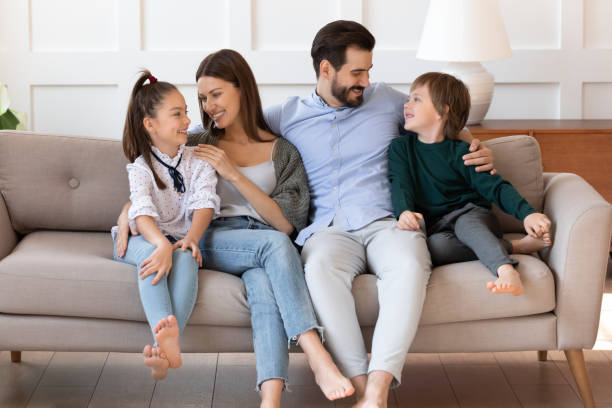 istock Affectionate young parents relaxing on sofa, cuddling small children. 1257040835