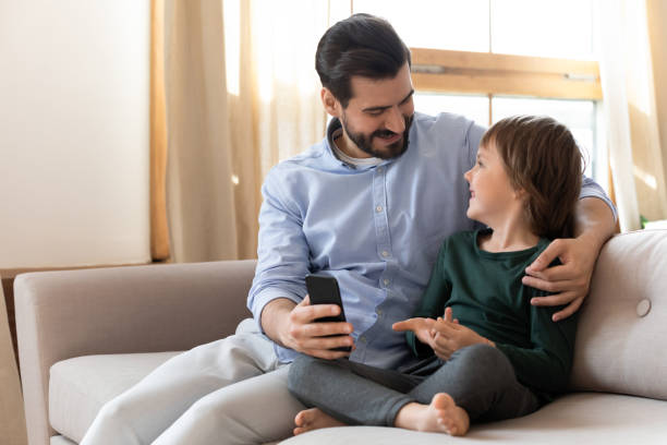 istock Happy dad cuddling small child son, showing funny mobile app. 1257040861