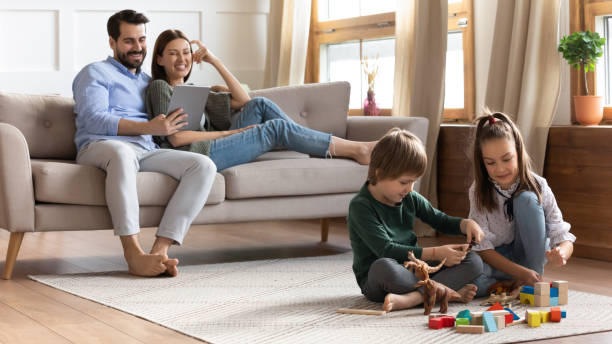 istock Young couple resting on comfortable sofa, while children playing toys. 1257040881