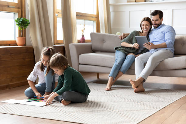 istock Playful little children drawing pictures while parents using digital tablet. 1257040882