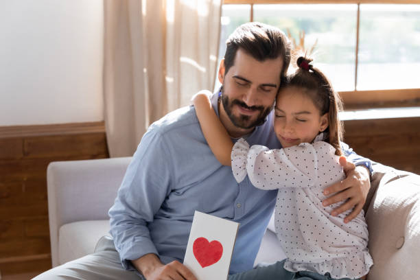 istock Young father hugging little daughter, feeling grateful for birthday congratulations. 1257040942