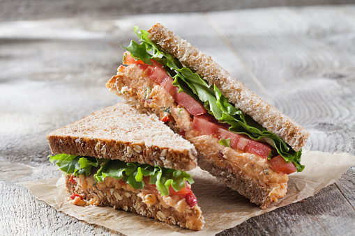 A perfect healthy meat sandwich, made from integral bread, ham, green salad, cherry tomato salsa, local organic seasoning, herbs and spices. Representing a healthy lifestyle, healthy eating, a wellbeing, modern city life, street food culture and a perfect brunch gourmet delicatessen.