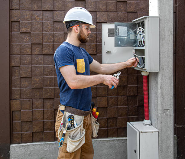 istock Electrician Builder at work, examines the cable connection in the electrical line in the fuselage of an industrial switchboard. Professional in overalls with an electrician's tool. 1257044326