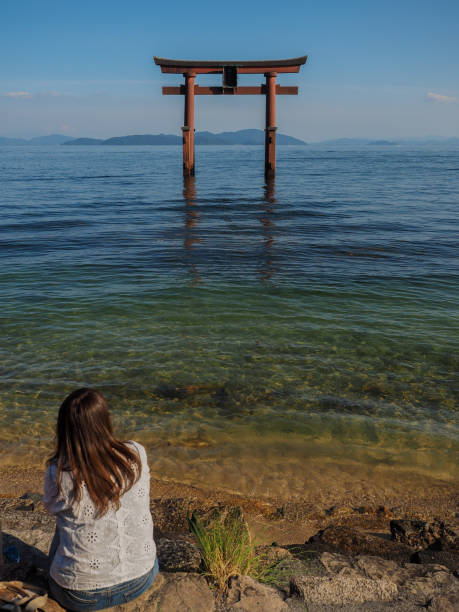 Enjoying the Torii view A woman looks out at the Shirahige Jinja Torii gate on Lake Biwa in Takashima, Japan on August 2017 otsu city stock pictures, royalty-free photos & images