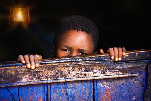 african child behind the wooden wall in the night in a  house in an African village in Botswana