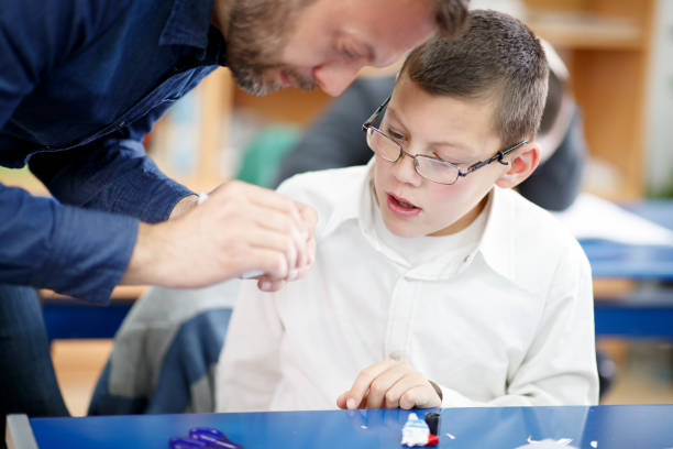 istock Special needs boy paying attention on how's tutor folding paper 1257046548