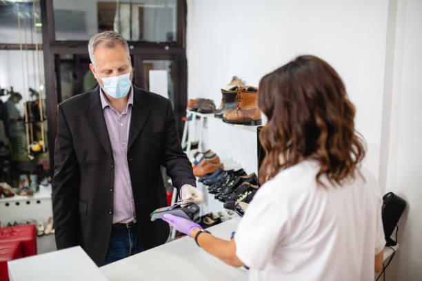 cliente con maschera protettiva per il viso e guanti che pagano con carta di credito al dettaglio - shoe store sales clerk customer foto e immagini stock