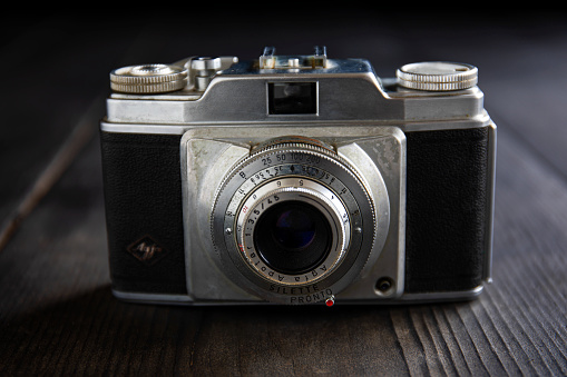 Detail photo of a metal-bodied analog camera and 35mm film taken in a light box with studio light effect