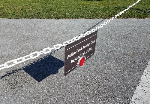 authorized access only beyond this point sign with chain and asphalt