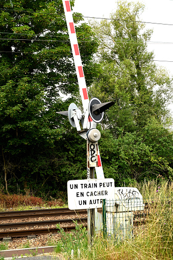 Around Paris, France - june 20 2020 : Railroad crossing in the countryside. Automatic railroad crossing with trees in the background