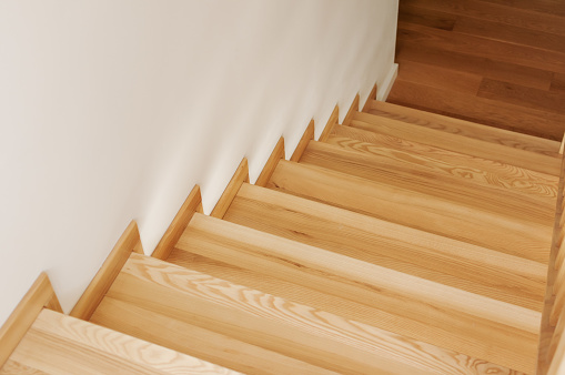 The stairs are made of wood in a modern, elegant style. The railings are made of laminated glass and wood.