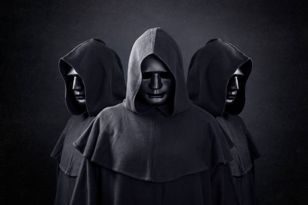grupo de tres figuras aterradoras en capas encapuchadas en la oscuridad - capucha fotografías e imágenes de stock