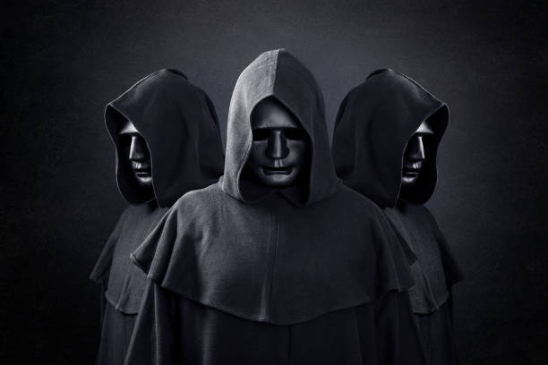 Group of three scary figures in hooded cloaks in the dark Group of three scary figures in hooded cloaks in the dark hood clothing stock pictures, royalty-free photos & images