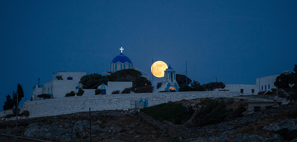 Full moon on dark blue sky above Kastriani monastery. Greece. Kea island, Traditional greek island architecture, white and blue colors church and auxiliary buildings