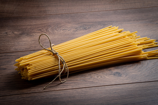 raw spaghetti on a wooden table. uncooked pasta.