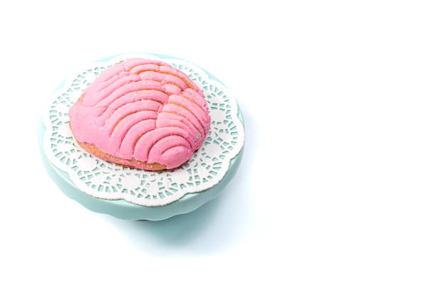 rosa mexikanische süße brot concha auf einem deckchen und blauen kuchenstand - gee gee stock-fotos und bilder