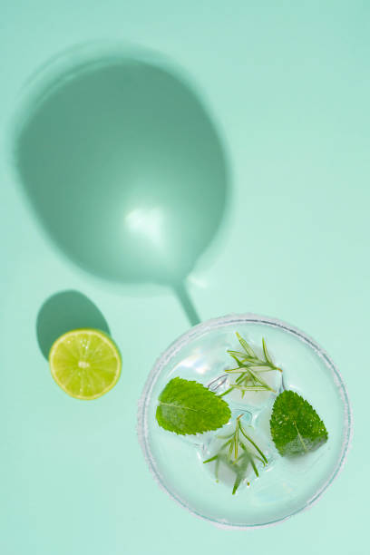 rosmarin-cocktail mit minzblättern in eiswürfeln auf grünem minzhintergrund - glass ice tonic water frozen stock-fotos und bilder