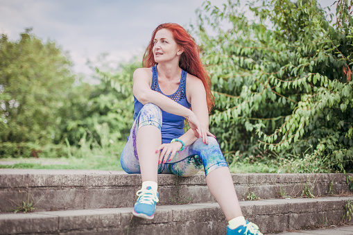 Mature red headed woman sitting on the stairs after a jog