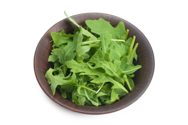 istock Fresh leaves of arugula in ceramic brown bowl isolated. 1257071029