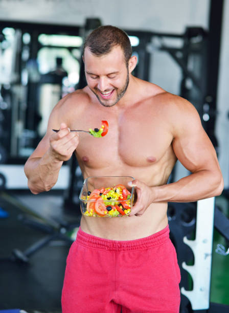 istock Powerful athletic man with great physique eating a healthy salad. 1257073289