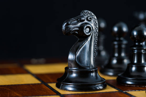 Chess with a black knight in an open area. Black background. stock photo
