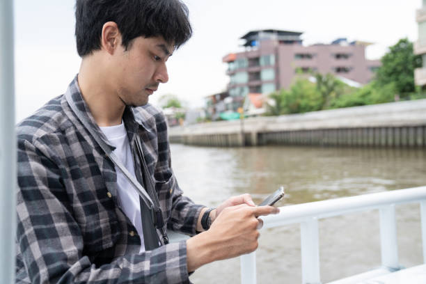 istock man sitting on boat with hold mobile phone 1257074591