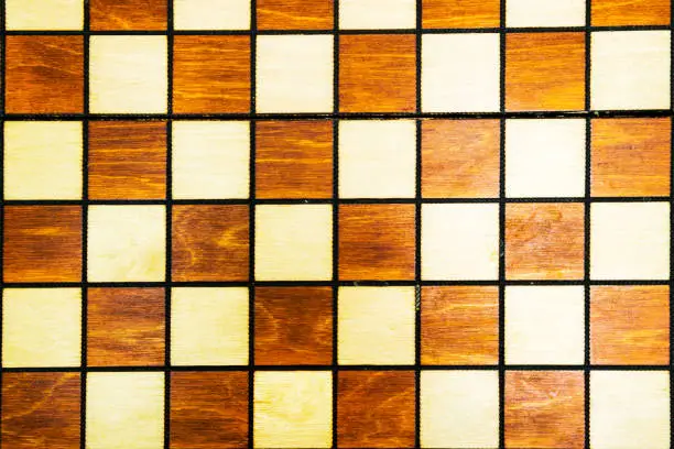 Photo of Wooden background of a chessboard. Vintage texture of a chess Board. White and black squares for a popular, favorite game.