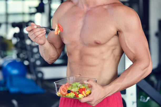 istock Powerful athletic man with great physique eating a healthy salad. 1257075997