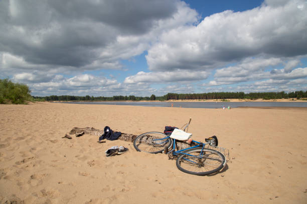 Bicycles lie on the beach in summer near the river.