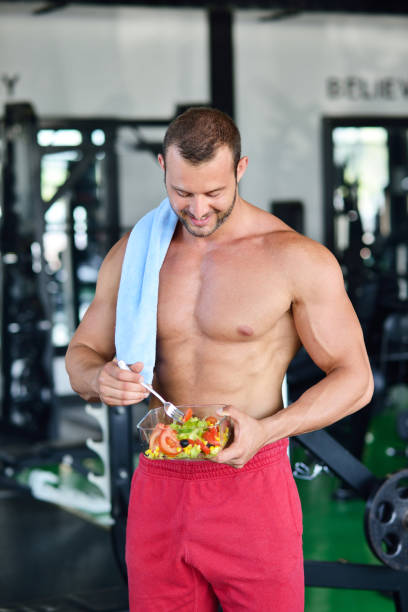 istock Powerful athletic man with great physique eating a healthy salad. 1257078513