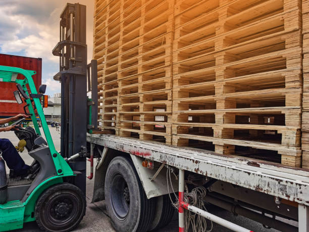 istock Worker driving forklift to loading and unloading wooden pallets from truck to warehouse cargo storage, shipment in logistics and transportation industrial, wood pallets stack 1257082477