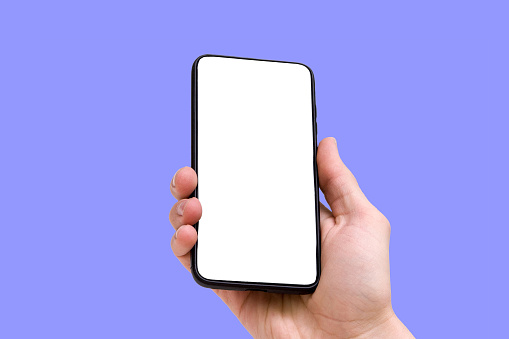A person holds a smartphone with an empty screen on a blue background, close-up of the hand. High quality photo