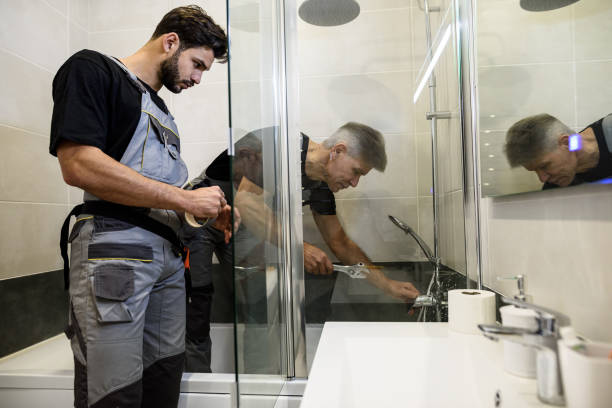 istock Two plumbers, workers in uniform working, fixing water tap in bathtub using wrench and sticky tape indoors. Repair service concept 1257084411