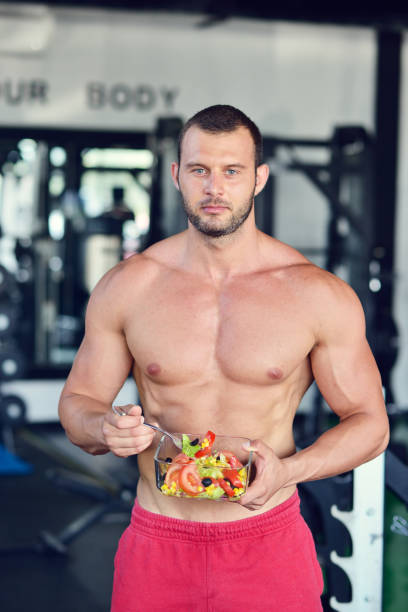 istock Powerful athletic man with great physique eating a healthy salad. 1257085383